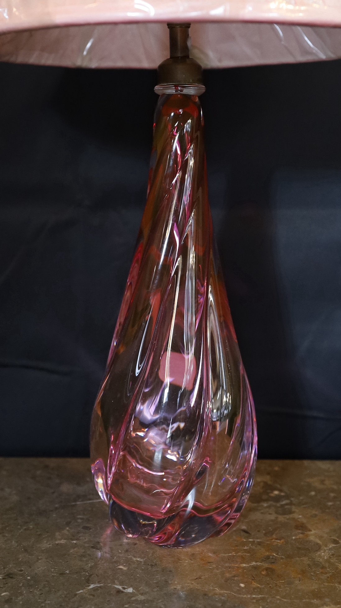 A 1960s Val Saint Lambert cranberry tinted glass table lamp, of twisted form, with replacement pleated silk shade, height 36cm